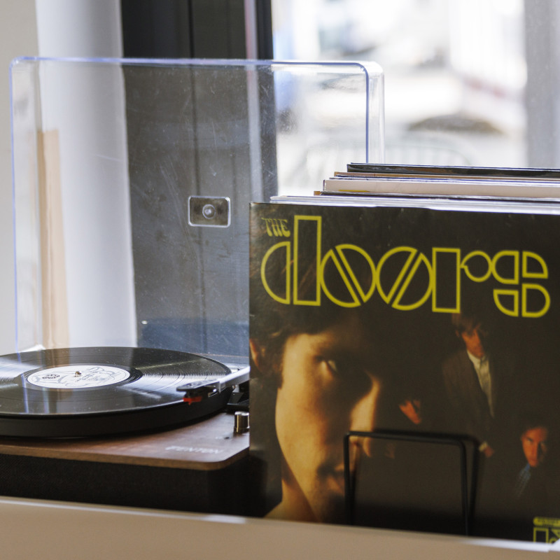 Schallplattenspieler mit Vinyl-Alben, darunter The Doors, auf einer weißen Ablage in einem stilvollen Hotel.