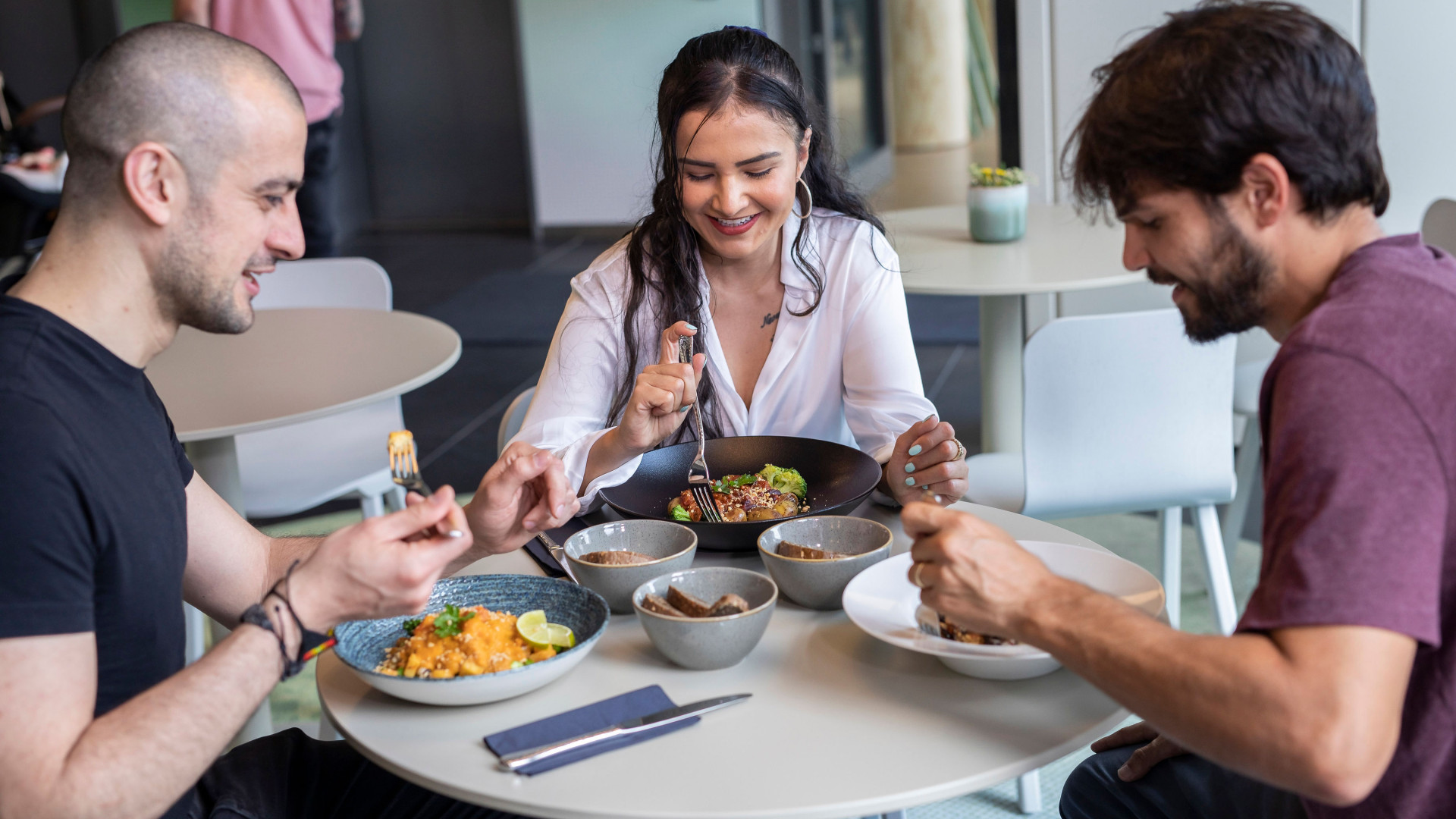Zwei Männer und eine Frau genießen ihr Frühstück im LyvInn Hotel.