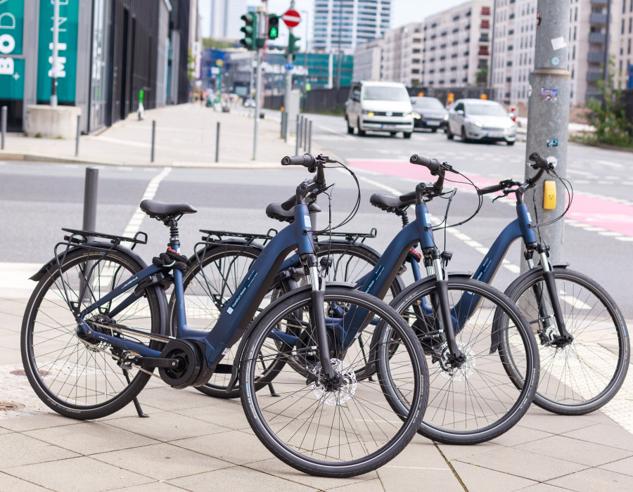 Mehrere Fahrräder stehen nebeneinander auf dem Bürgersteig in einer modernen städtischen Umgebung.